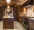 wooden walls, wooden floor, central island, gas stove, wooden cabinets, hanging light