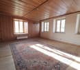 empty room, wooden floor, wooden walls, large carpet, three windows, heater