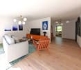 white walls, wooden floor, glass door, light fixtures, sofa, TV stand, armchair, decorative items