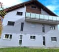 3 story house, white exterior, brown wooden accents, multiple windows, balcony on second floor