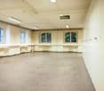 Large open room with high ceilings, arched windows, and a 'Not ausgang' (emergency exit) sign. The room has a concrete floor and appears to be a multipurpose space, possibly used for events or activities.
