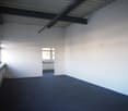 empty room, white walls, blue carpet, windows, radiators, doorway to adjacent room with window and radiator