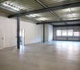 large open space, metal beams, white walls, open doors, concrete floor, windows