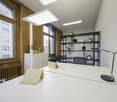 white desk, adjustable lamps, wooden radiators, large windows, shelving with plants