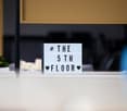 counter with sign board indicating the fifth floor, plant in the left corner, window in the background