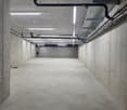 Empty basement with concrete walls, ceiling and floor, metal pipes and lights