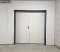 Empty room with white walls, concrete floor, double doors, and a power outlet on the wall