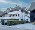 white building, red shutters, balconies, cobblestone driveway, hedges, mailbox
