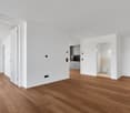Modern room with wood flooring, white walls, large open space, large closets, kitchen and bathroom