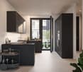 Modern kitchen with dark cabinets, black countertops, stainless steel appliances, and a balcony/terrace visible through the large windows.