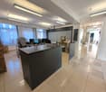 modern office with tiled floor, a large reception desk, monitors, printer, cabinets, and bright lighting