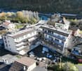 4 story building, balconies, windows, roof, driveway, vehicles parked, landscape area, trees