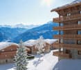 wooden chalets, snow-covered roofs, balconies, pine trees, snowy mountains