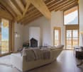 Spacious living room with high wooden ceiling, large windows, fireplace, and comfortable seating area