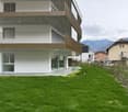 modern white building, glass walls, metal railings, balcony, green lawn