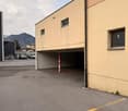 Building with a garage and parking lot, beige walls, red and white pole, mountains in the background