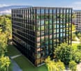 A modern, multi-story office building with a glass facade surrounded by lush greenery and trees. The building appears to be situated in a park-like setting with walking paths and landscaping visible in the foreground.