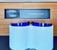 Wooden wall paneling, white reception desk, blue accent lighting, wall mounted television, carpeted floor.