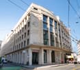 A large, multi-story commercial building with a distinctive Art Deco-style facade. The building has a prominent sign that reads 'RHONE' and features decorative elements and sculptures on the exterior. The building appears to be located in an urban setting