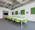 empty meeting room, long white table, green chairs, white walls, green panels, TV, clock