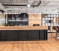 modern reception desk, black and wooden design, two monitors, two potted plants, hanging lamps, metal shelves, wooden chairs