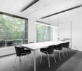 White meeting room, glass wall, white desk, chairs, carpet, suspended lights, white ceiling