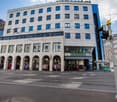 white and blue facade building, many windows, arched entrance, retail stores on the ground floor
