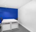white desk, two black swivel chairs, white and blue wall