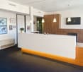 modern reception area with a counter, desk, wooden cabinets, pictures on the wall, and an air conditioning unit