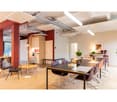 meeting room, large rectangular table, black chairs, floor lamp, wooden floor, white walls, plants, picture on wall, red columns