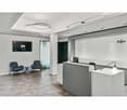 office lobby, two chairs, desk, black wall-mounted monitor, monitor on desk, gray walls, white ceiling