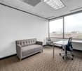 empty office room, carpet floor, two chairs, gray couch, desk, windows
