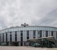 Modern circular building with large glass windows, gray exterior, and a curved entrance with a canopy. The name 'Regus' is displayed prominently on top.