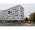 Commercial office building, white facade, multiple floors, glass windows, red traffic light
