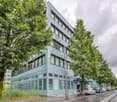 modern office building, glass facade, multiple windows, parking lot, trees, street
