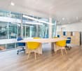 office meeting room, wooden flooring, glass walls, large table, blue and yellow chairs, cabinets