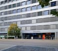 commercial building, multiple windows, 'conex' sign on facade, aldi store, parking spaces, streetlights, tree