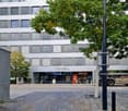 Modern building exterior, several floors, glass windows, signage for 'conex', ADI and a bakery shop.