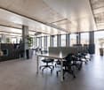 modern open space office with desks, chairs, large windows, plants