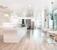 modern open kitchen, modern cabinets, white countertops, wooden flooring, pendant lighting, large windows