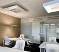 modern office with white desks, white chairs, white lamps, beige wall, glass doors, ceiling lights