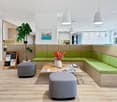 modern interior, wooden floor, green sofa, wooden coffee table, flower vase, blackboard with text, round ottomans, hanging lamps