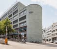 Regus building, multiple floors, glass windows, bicycles parked outside, trees, cars parked on the street