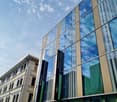 modern office building, glass facade, reflective windows, multiple floors, adjacent to another building