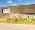 Modern house, raised ground floor, large windows, concrete exterior, green grass, road