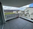 Balcony with a view of the surrounding buildings and landscape, tile flooring on the balcony, metal railing