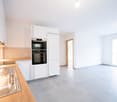 modern kitchen with integrated appliances, wooden countertop, white cabinets, tiled floor