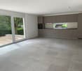 empty room with tiled floor, sliding glass doors, kitchen with oven, countertops, sink, and cabinets