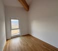 Empty room, large window, wooden floor, white walls, outdoor view