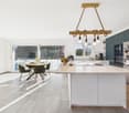 modern kitchen, white countertops, central island, modern chandelier, dining table, green chairs, large glass doors, terrace view